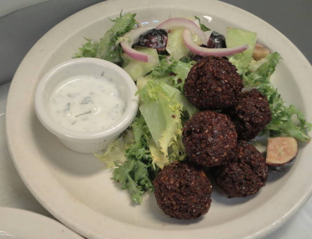 Crispy chickpea falafel witha salad of curly endive, figs, melon, red onion with a tahini vinaigrette, served with sauce blanche.