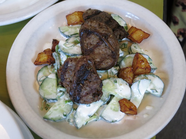 Jura-style morteau sausage on a salad of cucumber, spring onions, chives and crispy potato croutons in a horseradish cream.