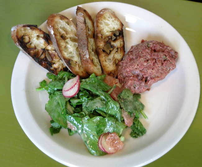 Grass-fed beef tartare serve with a salad of arugula, radishes, grapefruit and grilled baguette