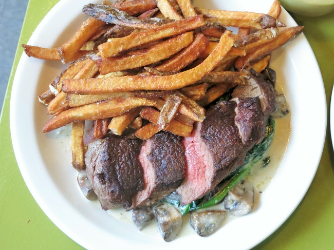 Pan roasted grass-fed petit sirloin steak, served with pommes frites and spinach simmered with cremini mushrooms, sultanas and chevre cream