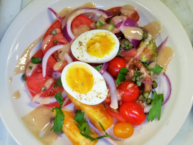 Salad of beefsteak and heirloom tomatoes, red onion, capers, parsley, roasted garlic vinaigrette and a hard cooked egg.
