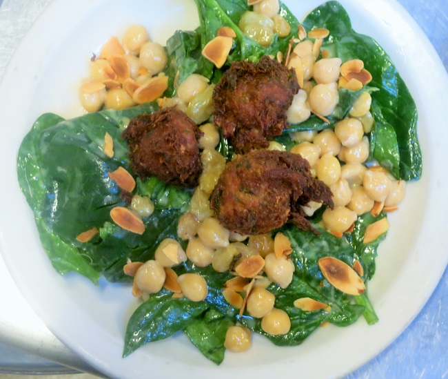 Curried salt cod fritters served on a salad of spinach, marinated chickpeas and toasted almonds with pastis vinaigrette