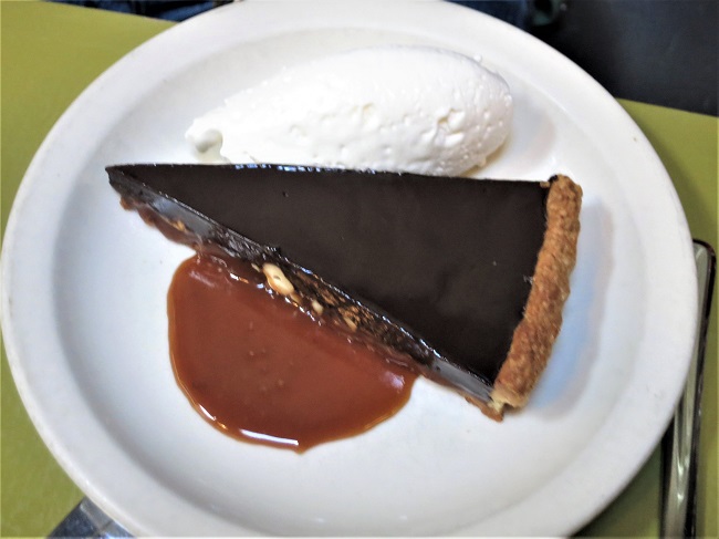 Chocolate ganache tart baked with sea-salt caramel, cashews and sweet pastry crust, served with whipped cream