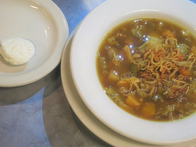 Alsace-style soup with cabbage, Kabocha squash, rutabaga, caraway seeds, and dark beer broth, garnished with crispy shallot and horseradish cream