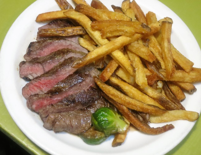 Grass fed petit sirloin steak frites served with roasted Brussels sprouts finished with black currants, parsley and anchovy butter